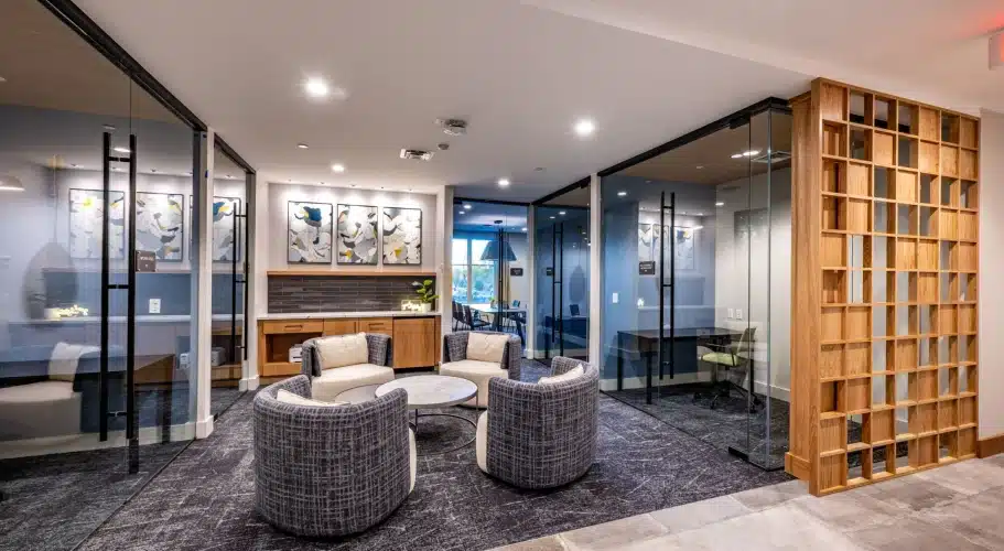 Contemporary business center with enclosed glass offices, soft seating, and modern wall art