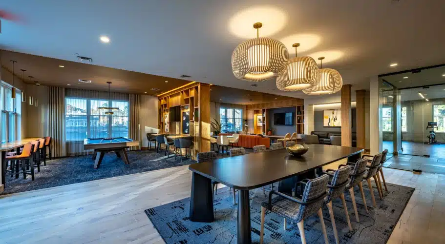 Spacious multi-use lounge with pool table, dining area, pendant lights, and open seating zones