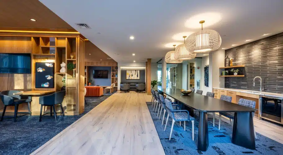Open community space featuring wooden finishes, kitchenette, and built-in shelving with art decor