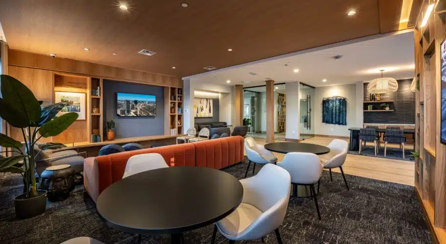 Comfortable community lounge with modern round tables, white chairs, and art-filled shelving
