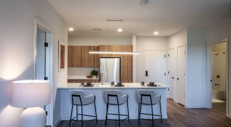 Contemporary kitchen with wood cabinetry, breakfast bar, and modern lighting over sleek island