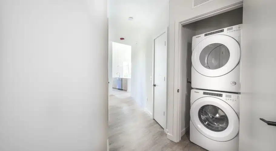Compact laundry space with Whirlpool washer and dryer tucked into bright apartment hallway
