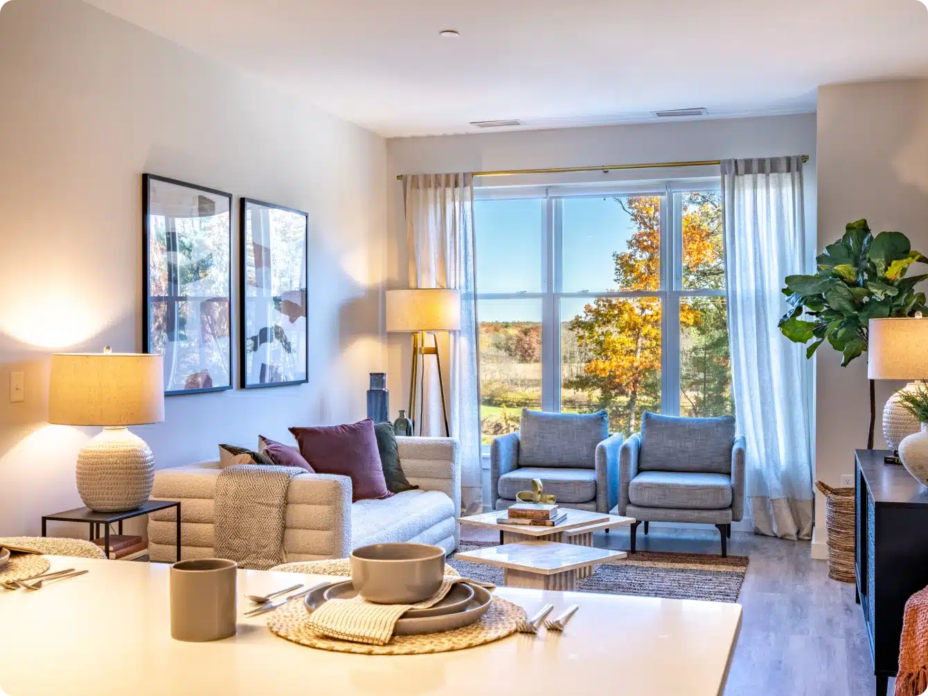 Brightly lit apartment living room with two chairs by window and cozy neutral decor