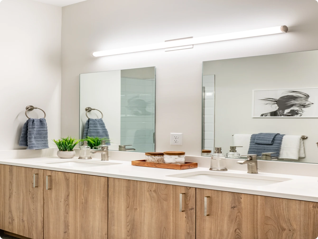 Sleek bathroom with double vanity, wood cabinets, minimalist lighting, and twin square mirrors