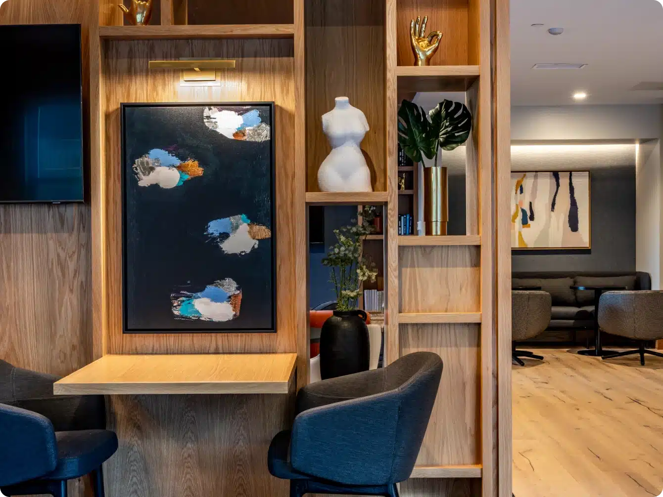 Apartment study nook with black chairs, abstract artwork, and open wooden shelving décor
