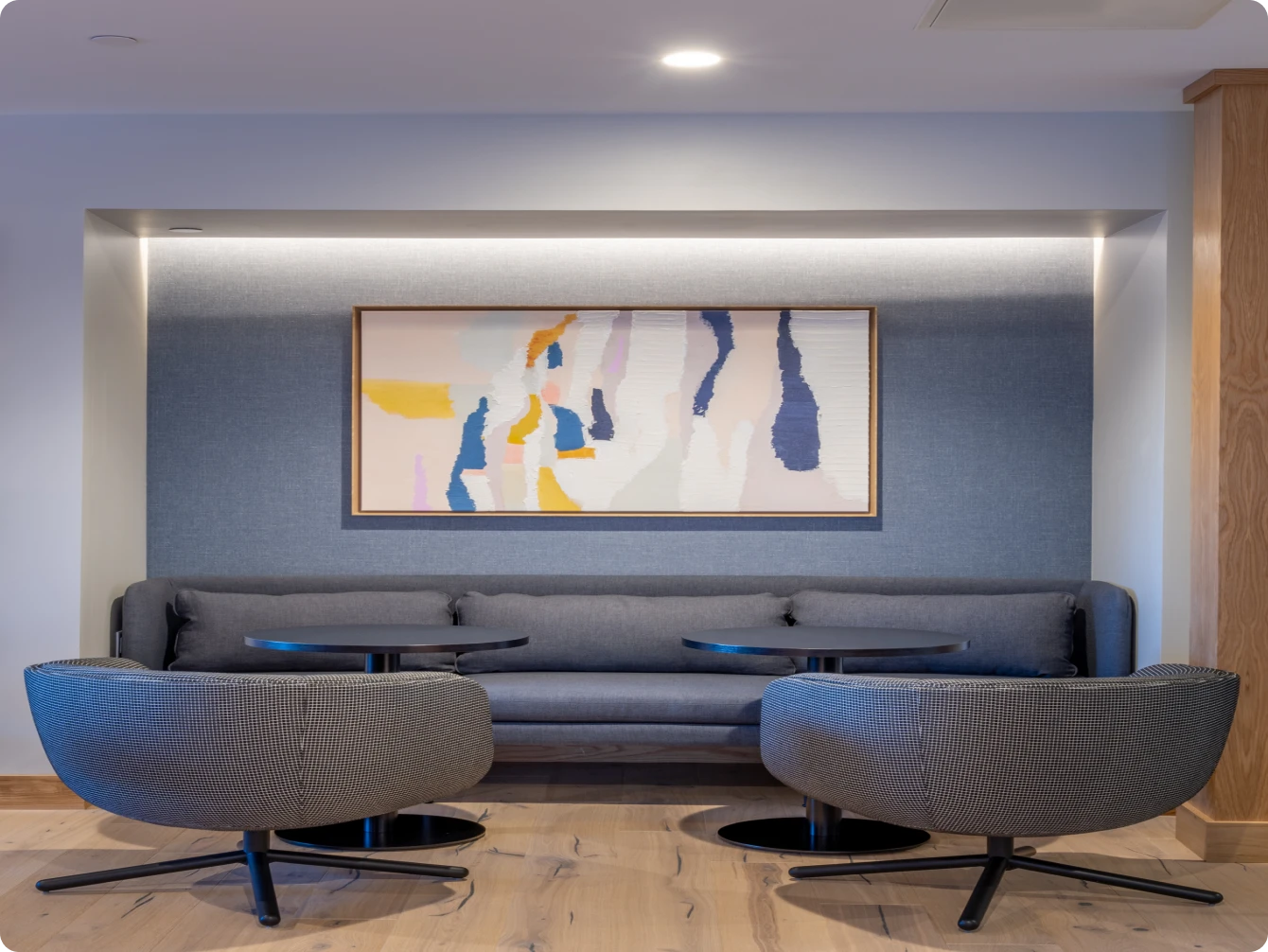 Cozy lounge area with grey seating and large framed abstract artwork on blue accent wall