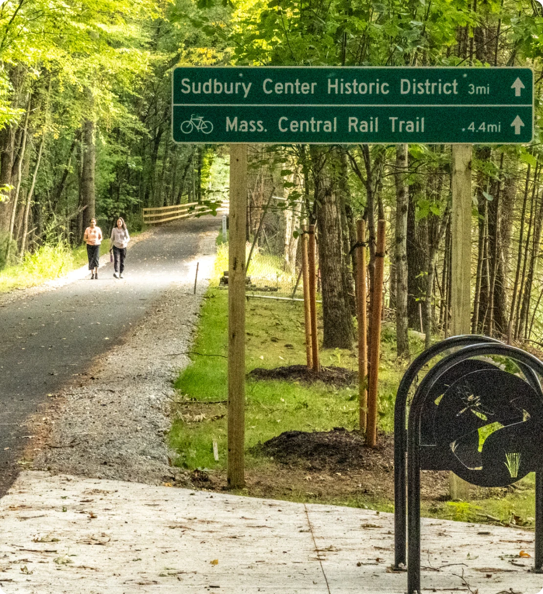 Green trail sign marking distances to Sudbury Center and Mass Central Rail Trail