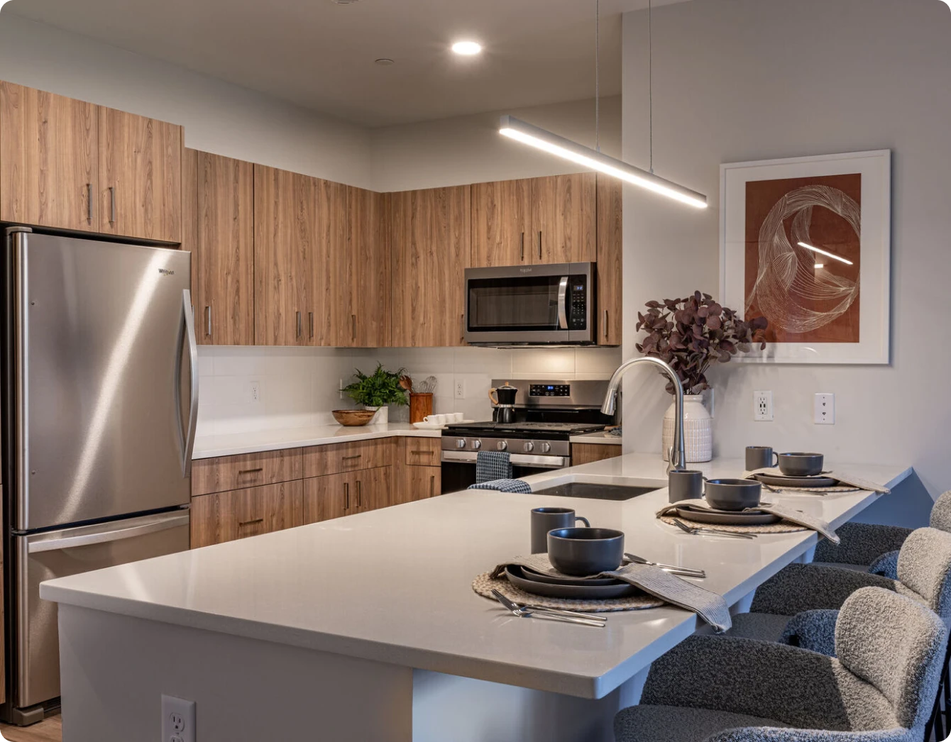 Modern kitchen with wooden cabinets, stainless appliances, and a sleek white quartz island