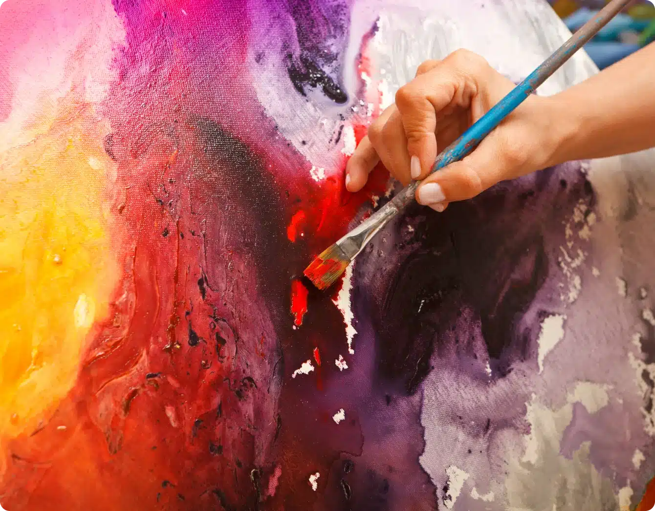 Artist hand painting colorful abstract canvas with bold brushstrokes and vivid colors