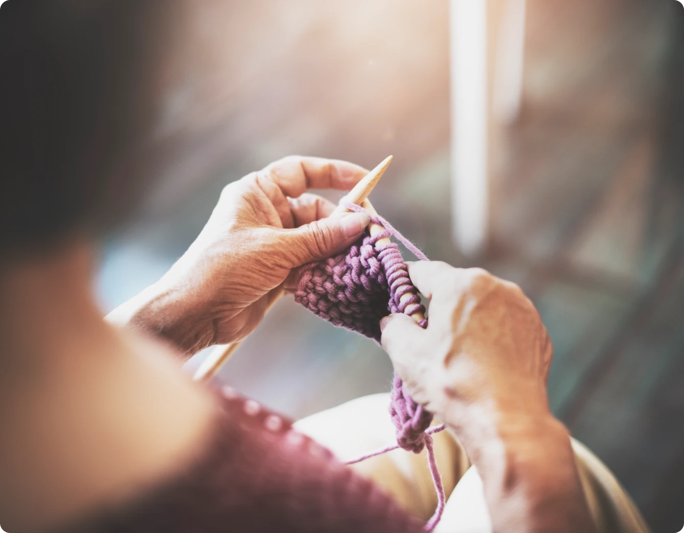Experienced hands knitting with precision using pink wool yarn.