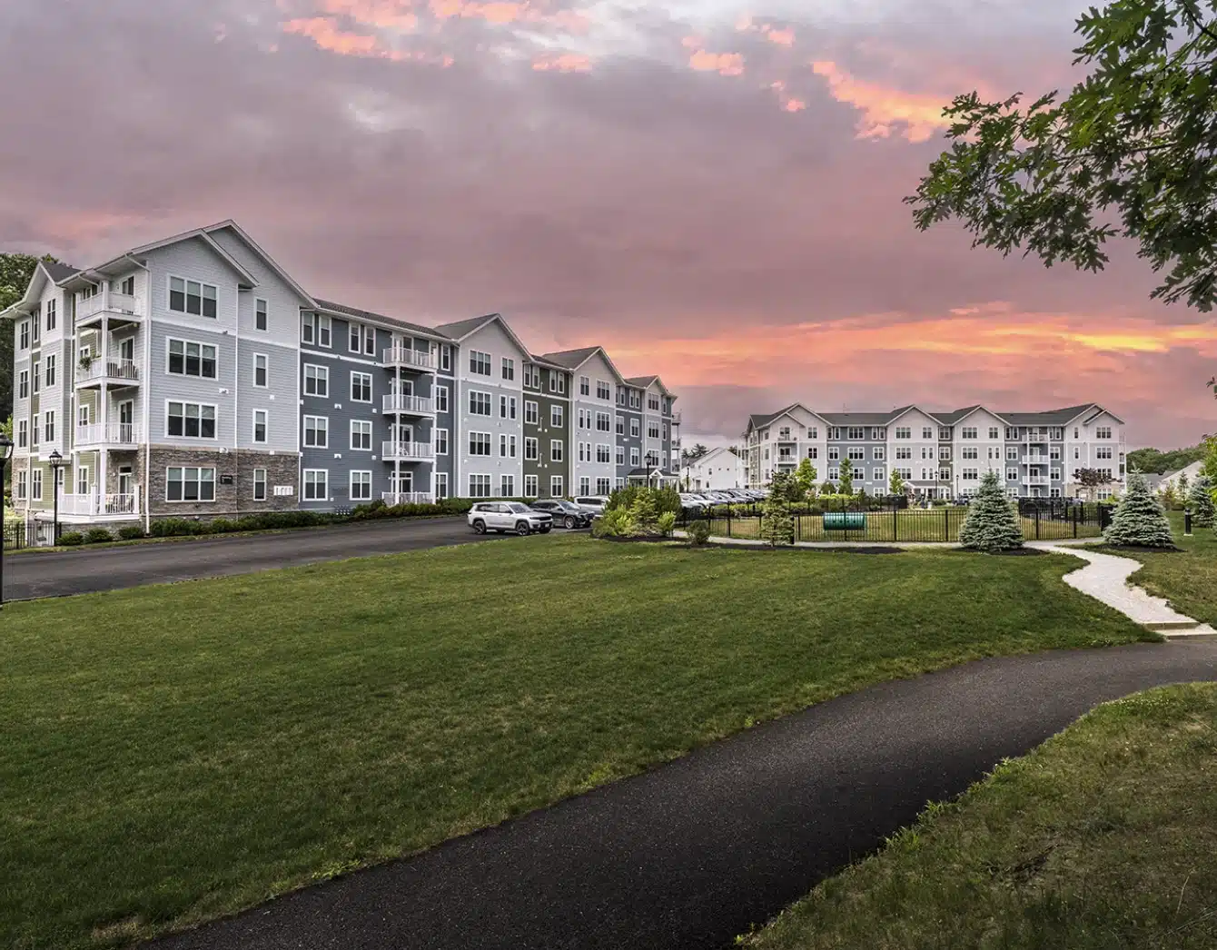 Modern apartment complex with manicured landscaping and sunset sky creating vibrant twilight ambiance
