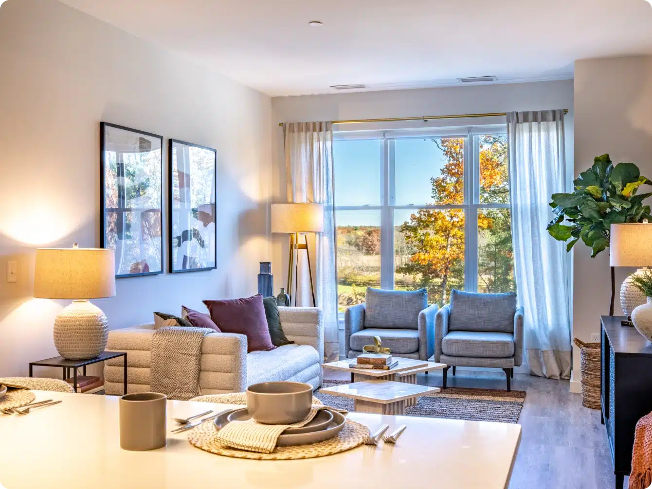 Open-concept apartment kitchen with wood cabinetry, island seating, and view into living room